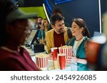 Happy couple buying drink and snack before movie projection in cinema.