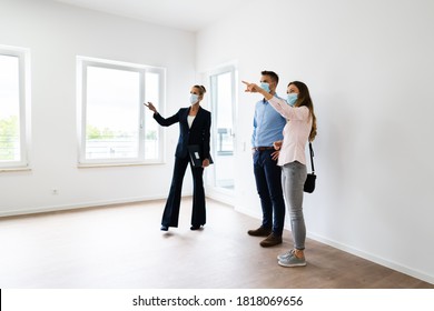 Happy Couple Buying New Home With Realtor Wearing Face Masks - Shutterstock ID 1818069656