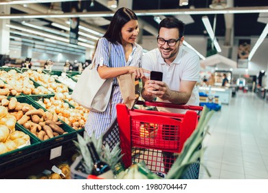 Happy couple buying vegetables at grocery store or supermarket - shopping, food, sale, consumerism - Powered by Shutterstock