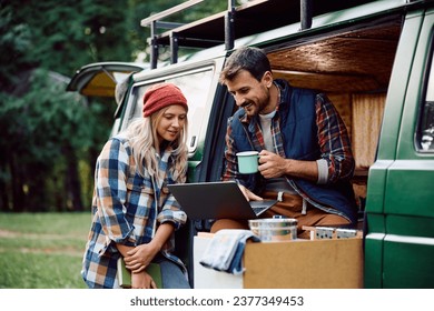 Happy couple of campers surfing the net of on laptop while relaxing in their van in nature.  - Powered by Shutterstock