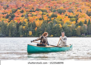 Happy couple canoeing in a lake in Canada - Colourful trees and leaves in background at autumn foliage peak - Young couple enjoying nature and adventure,  wanderlust and nature concepts - Powered by Shutterstock