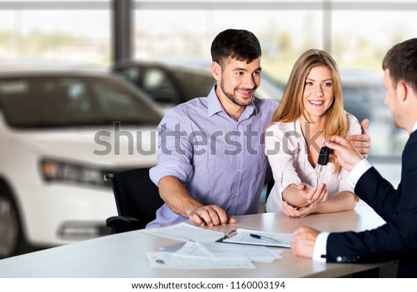 Happy couple\
with car dealer in auto show or\
salon