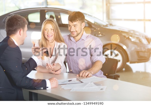 Happy couple\
with car dealer in auto show or\
salon
