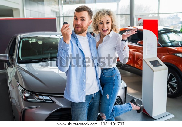 Happy couple in car dealership on the background of\
their new car