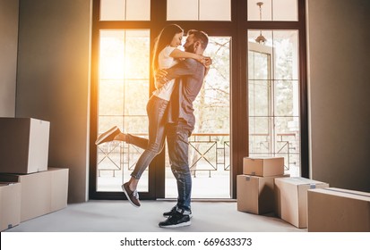 Happy couple with cardboard boxes in new house at moving day.