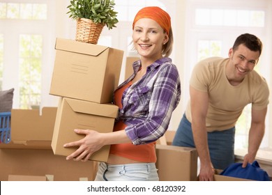 Happy couple carrying boxes at moving house.