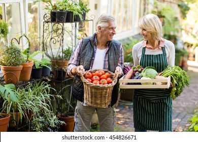 Happy couple carrying fresh vegetables outside greenhouse - Powered by Shutterstock