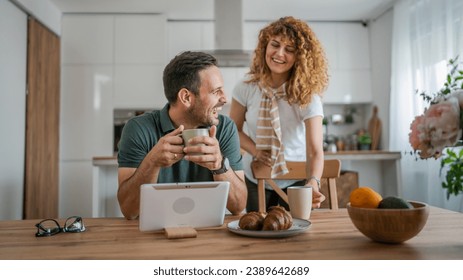 happy couple caucasian adult man and woman husband and wife morning routine use digital tablet while have a cup of coffee or tea bonding and love at home bright photo copy space