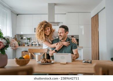 happy couple caucasian adult man and woman husband and wife morning routine use digital tablet while have a cup of coffee or tea bonding and love at home bright photo copy space - Powered by Shutterstock