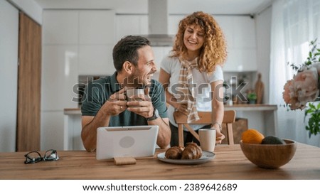 happy couple caucasian adult man and woman husband and wife morning routine use digital tablet while have a cup of coffee or tea bonding and love at home bright photo copy space
