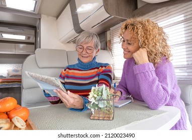 Happy Couple Of Caucasian Women Multigenerational Family Sitting Inside A Camper Van Motor Home Looking At Map Planning Next Journey. Lifestyle And Travel Modern People, Vacation Journey Concept