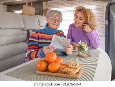 Happy Couple Of Caucasian Women Multigenerational Family Sitting Inside A Camper Van Motor Home Looking At Map Planning Next Journey. Lifestyle And Travel Modern People, Vacation Journey Concept