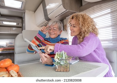 Happy Couple Of Caucasian Women Multigenerational Family Sitting Inside A Camper Van Motor Home Looking At Map Planning Next Journey. Lifestyle And Travel Modern People, Vacation Journey Concept