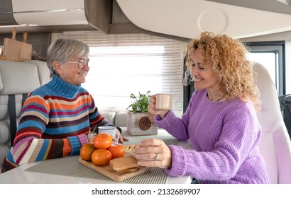 Happy Couple Of Caucasian Women Multigenerational Family Sitting Inside A Camper Van Motor Home Looking Enjoying Coffee Break. Lifestyle And Travel Modern People, Vacation Journey Concept