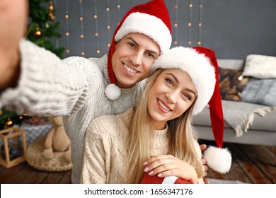 Happy Couple With Christmas Gift Taking Selfie At Home