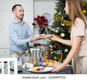 Happy Couple Cleaning Festive Table After Christmas Dinner