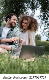 Happy Couple Clinking Glasses Of Wine While Watching Movie On Laptop Outside