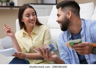 Happy Couple Counting Money In Living Room