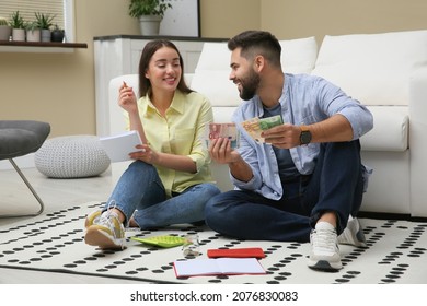 Happy Couple Counting Money On Floor At Home