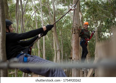 Happy couple crossing through a zip line in the forest