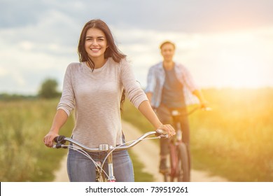 The happy couple cycling near the field