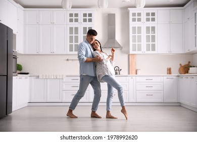 Happy Couple Dancing Barefoot In Kitchen. Floor Heating System