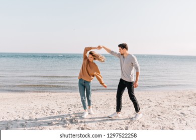 Happy couple dancing at beach. Outdoor shot of excited girl enjoyng weekend at sea. - Powered by Shutterstock