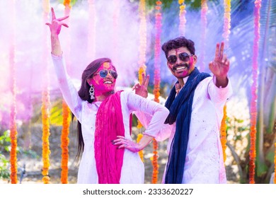 Happy couple dancing during holi festival celebration with colorful face and dress at ceremony - concept refreshment, entertainment and joyful - Shutterstock ID 2333620227