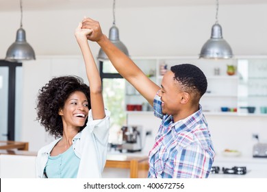 Happy couple dancing in kitchen at home