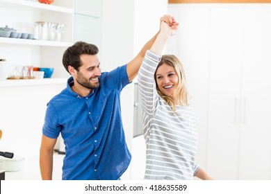 Happy Couple Dancing In Kitchen At Home