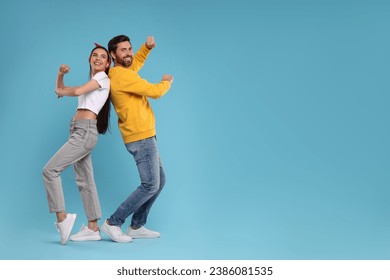 Happy couple dancing together on light blue background, space for text - Powered by Shutterstock