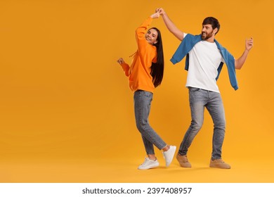 Happy couple dancing together on orange background, space for text - Powered by Shutterstock