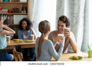 Happy couple dating, drinking coffee, sitting separately from group of mixed race people. Smiling friends meeting in cafe, laughing, having fun together, young guy got acquainted with attractive girl.