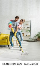 Happy Couple Doing Spring Cleaning In Living Room