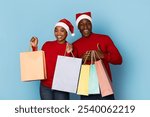 A happy couple dressed in red sweaters and Santa hats holds colorful shopping bags. They are filled with excitement, embodying the holiday spirit as they celebrate Christmas.