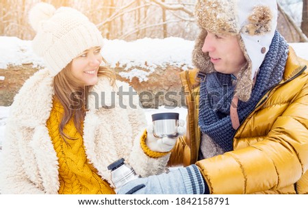 
happy couple drink hot tea in snowy forest.
