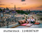 happy couple with a drink on rooftop of an cave house historical village of Ayvali Goreme Cappadocia, couple watch sunset Kapadokya