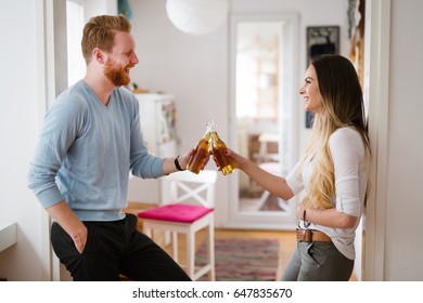 Happy Couple Drinking Beer And Toasting At Home