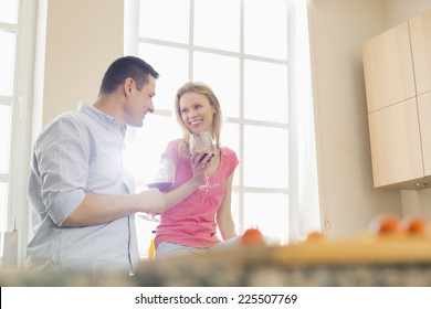 Happy Couple Drinking Red Wine In Kitchen