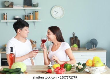 Happy couple drinking wine while cooking in kitchen