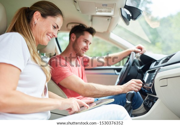 Happy couple driving in car using tablet computer\
as navigation system