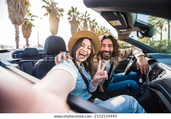 Happy couple driving convertible car on summer\
vacation - Tourists rent automobile on weekend road trip holiday -\
Transportation lifestyle\
concept
