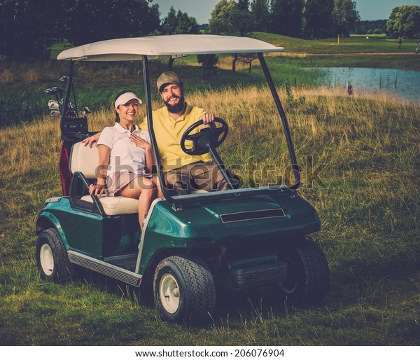 Happy couple driving golf cart\
