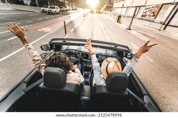 Happy couple driving on city\
street in convertible car - Friends rent cabrio auto on vacation -\
Roadtrip, freedom, travel and transport rental service\
concept