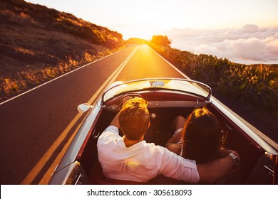 Happy Couple Driving on Country Road into the Sunset in Classic Vintage Sports Car 
