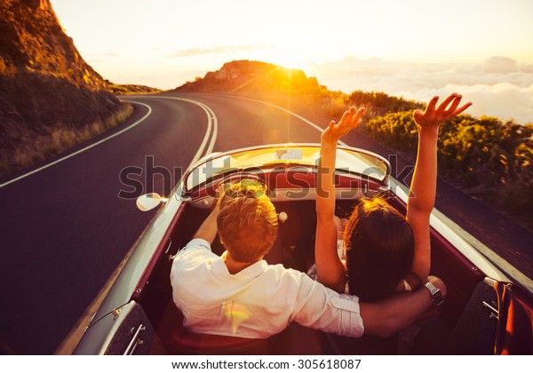 Happy Couple Driving on Country Road into the\
Sunset in Classic Vintage Sports Car\
