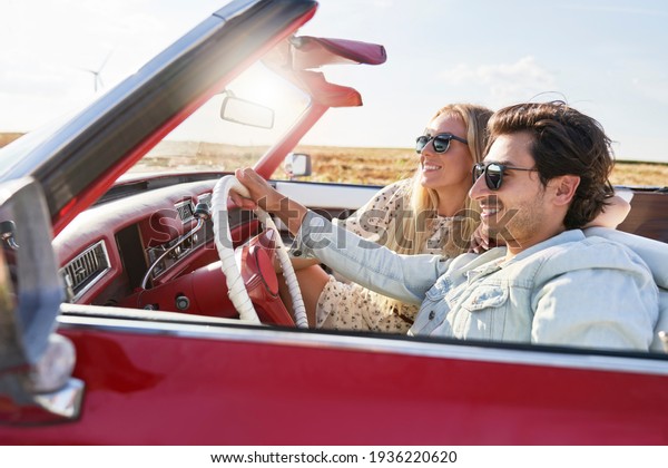  Happy couple driving in a red car at sunset       \
                      