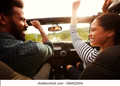 Happy Couple Driving In Their Car With Arms In The Air