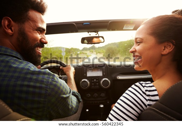 Happy\
couple driving in their car looking at each\
other