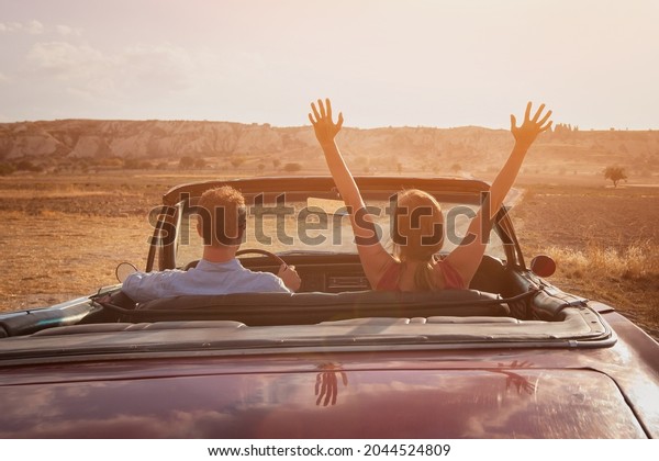 happy couple driving vintage classic sport car\
at sunset, luxury\
lifestyle
